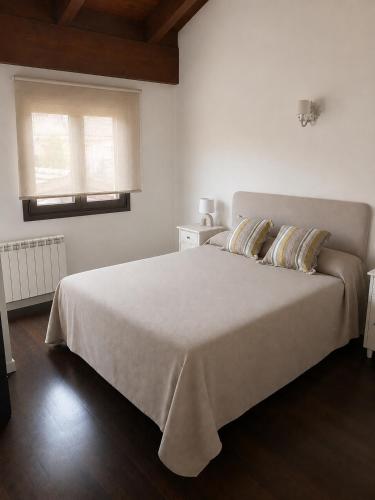 a white bedroom with a large bed and a window at Badaguás in Badaguás