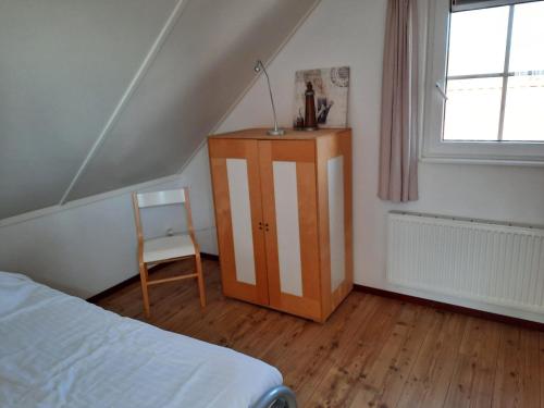 a bedroom with a bed and a cabinet and a window at Vakantiehuisjes Marsherne in Poppingawier
