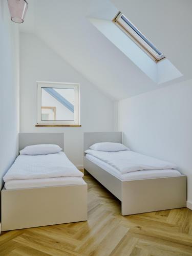 two beds in a room with white walls and wood floors at Domki Różane Nad Stawem in Stopnica