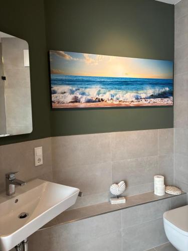 a bathroom with a sink and a picture of the ocean at Ostwall Terrassen Apartment in Bocholt