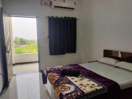 a bedroom with a bed and a window with a curtain at Jyoti Hotel and Restaurant in Desuri