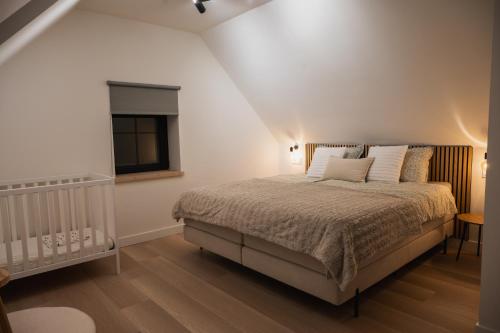 a bedroom with a bed and a window and a crib at De Viervoeters Hoeve in Ruiselede