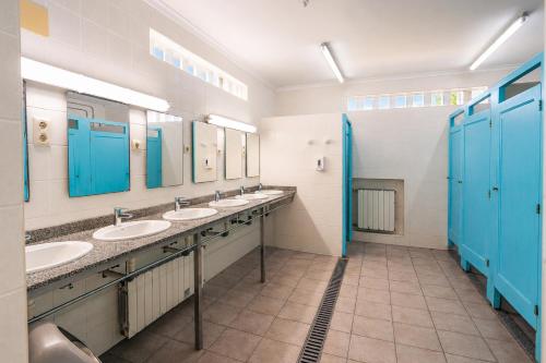 a bathroom with three sinks with blue doors and mirrors at Kampaoh Oliva in Oliva
