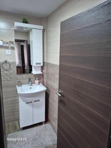 a bathroom with a sink and a wooden door at Brvnara K2 KONAK in Šljivovica