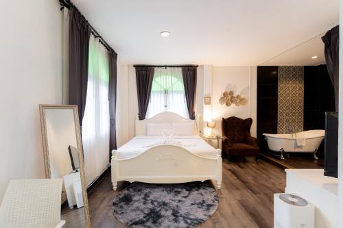 a bedroom with a white bed and a bath tub at Nidhra Lanna Hotel Chiang Mai in Chiang Mai