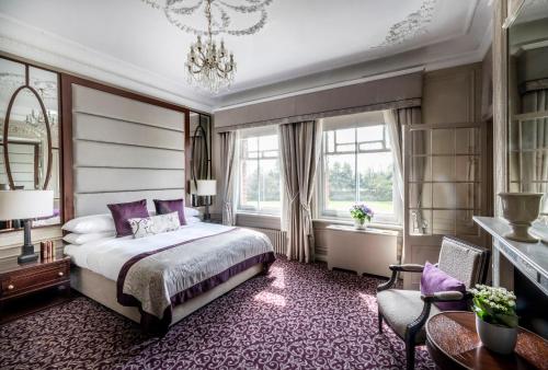 a bedroom with a bed and a chandelier at Woodlands Park Hotel in Cobham