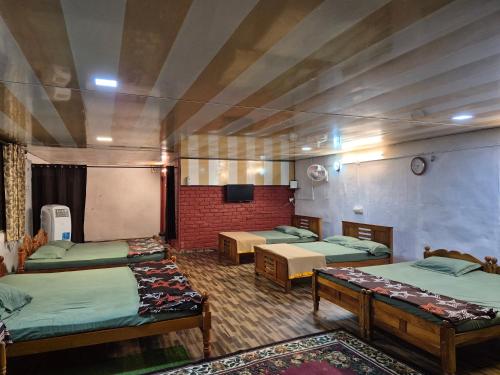 a room with four beds and a flat screen tv at BeingWild Resort in Masinagudi