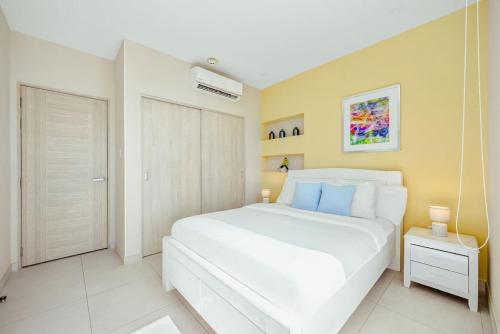 a bedroom with a large white bed with blue pillows at Aracari Residences by Bocobay - Luxury Condos 5 min Walk to Ritz and Palm Beach in Palm-Eagle Beach