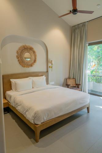 a bedroom with a large white bed and a window at The Ten in Siolim