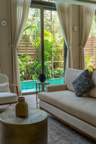 a living room with a couch and a large window at The Ten in Siolim