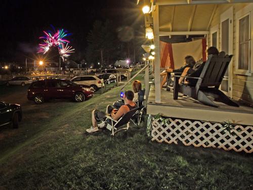 a group of people sitting in chairs on a porch at night at Half Moon Motel & Cottages in Weirs Beach