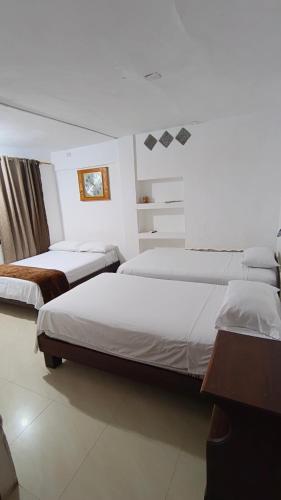 a hotel room with two beds and a desk at Hostal Fragata Puerto López in Puerto López