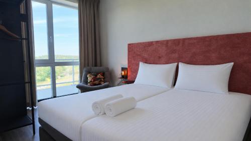 a bedroom with a large white bed with a window at Residentie De Zeester | De Wulk in Scherpenisse