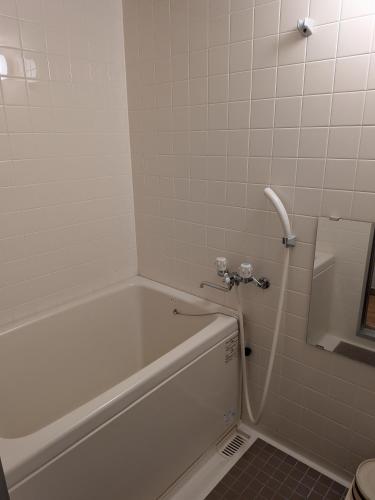 a bathroom with a white tub and a toilet at Shirafune Grand Hotel in Matsumoto