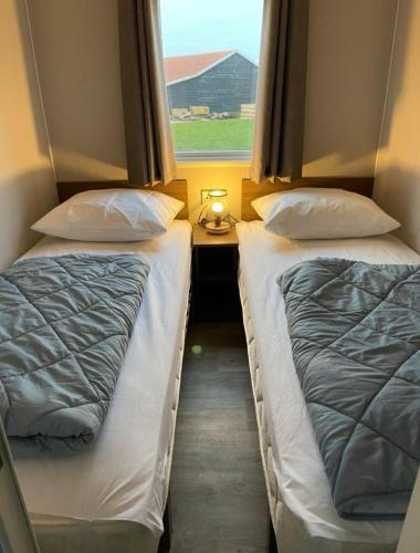 two beds in a small room with a window at SimpleStayHolland in Westerland
