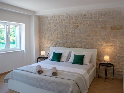 a bedroom with a large bed with green pillows at Seafront Stone House Sajbel in Novigrad Dalmatia