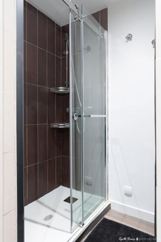 a glass shower in a bathroom with brown tiles at Festival de Cannes résidence de luxe piscine tennis in Vallauris
