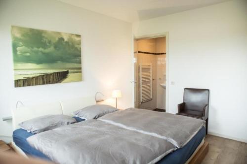 a bedroom with a bed and a painting on the wall at Weidevilla XXXL in Hollum