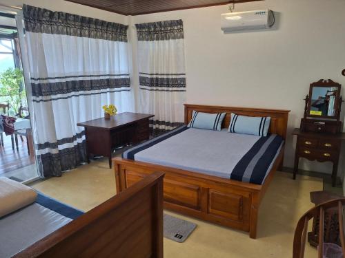 a bedroom with a bed and a desk and a window at Sunset Inn in Kandy