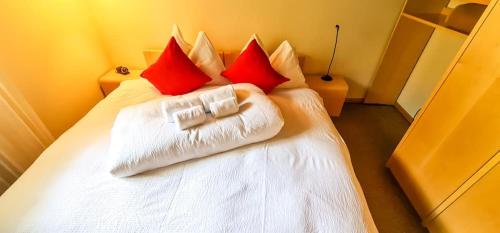 a bedroom with a white bed with red pillows at Bussalp Apartment - Aare Jungfrau AG in Grindelwald