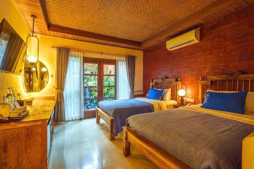 a bedroom with two beds and a window at Rama Phala Resort & Spa in Ubud