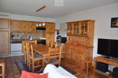 a kitchen with wooden cabinets and a table with chairs at Chalet Zou Derri 3 in Les Collons