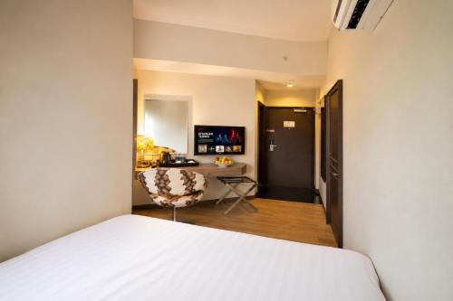 a bedroom with a white bed and a desk at Triima Inn Arenaa Melaka in Malacca