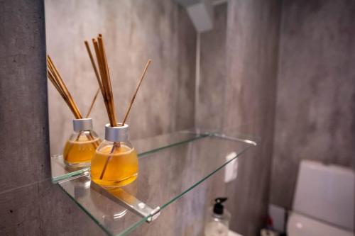 two bottles of oil on a glass shelf in a bathroom at City Center Getaway 9 by Berti in Stavanger