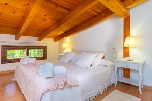 a bedroom with a large white bed with a wooden ceiling at Can Rosillo in Llucmajor