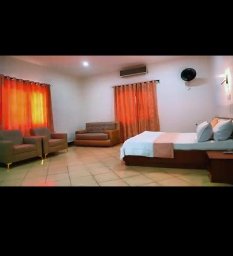 a bedroom with a bed and a chair and a couch at NBTE Hotels in Kaduna