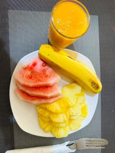 a plate of fruit with a banana and a glass of orange juice at Ebenezer resort hotel in Mbale