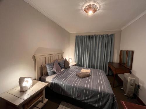 a bedroom with a bed and a table and a window at Dullstroom on the Dam in Dullstroom