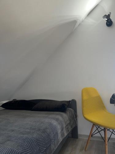 a bedroom with a bed and a yellow chair at Apartament Teo -Rewal in Rewal