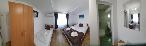 a room with two beds and a bathroom with a shower at Casa cu flori in Tuzla