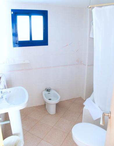 a white bathroom with a toilet and a sink at Apartamentos la barca in Benidorm