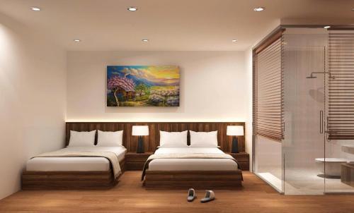 a bedroom with two beds and a painting on the wall at Thành Danh Hotel in Dong Hoi