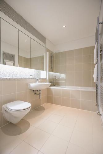 a bathroom with a toilet and a sink and a tub at IFSC Townhouse Apartments in Dublin