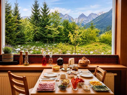 a table with food and a large window with a view at Vila Koman Jezersko in Zgornje Jezersko