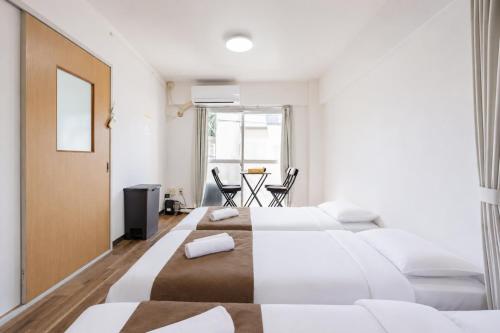 a bedroom with two beds and a table with chairs at Inage Good Place House in Chiba