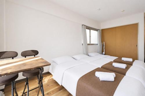 a bedroom with two beds and a table and chairs at Inage Good Place House in Chiba