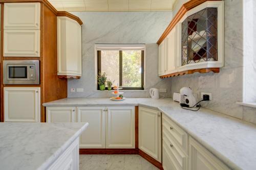 a kitchen with white cabinets and a window at Valleyside Heights Residence - Pool & Heated Jacuzzi in Is-Swieqi