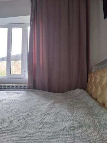 a bedroom with a large bed with a window at Cozy Stay Emir in Kazarman