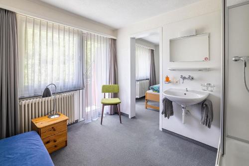 a bathroom with a sink and a bed and a mirror at Hotel Haus am Wald in Arosa
