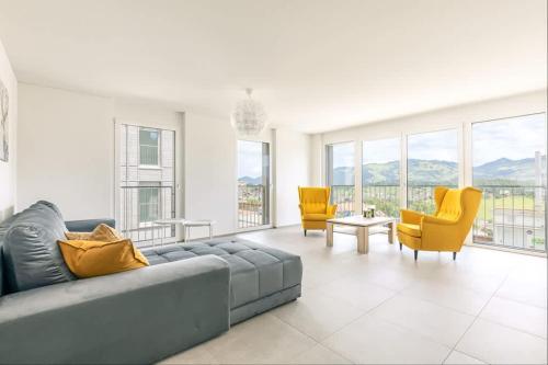 a living room with a gray couch and yellow chairs at Stockhorn Apartment - Aare Jungfrau AG in Spiez