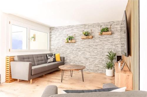 a living room with a couch and a brick wall at Alpin Chic - Aare Jungfrau AG in Grindelwald