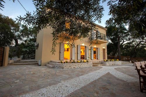 a house with a stone patio in front of it at Villa Praxithea in Lákka