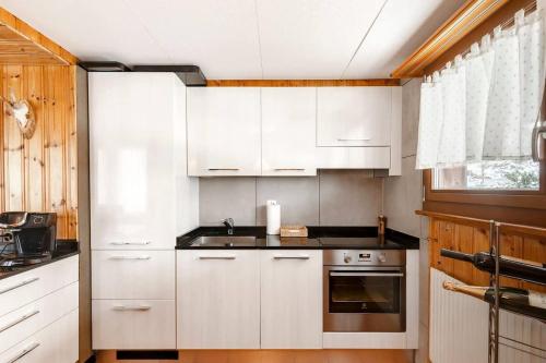 eine weiße Küche mit weißen Schränken und einem Fenster in der Unterkunft Sara in Axalp
