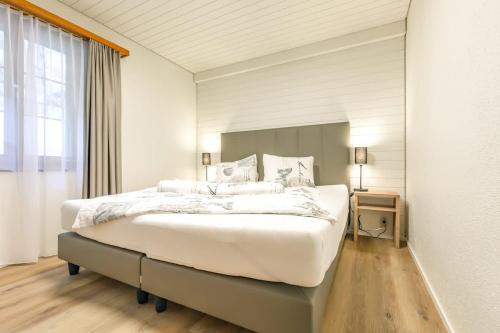 a large white bedroom with a large bed and a window at Kehr Apartment - Aare Jungfrau AG in Grindelwald