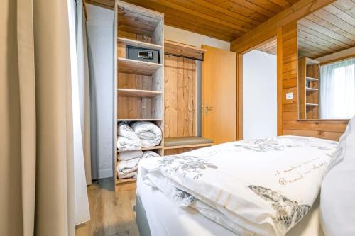 a bedroom with a bed and a closet with towels at First Apartment - Aare Jungfrau AG in Grindelwald