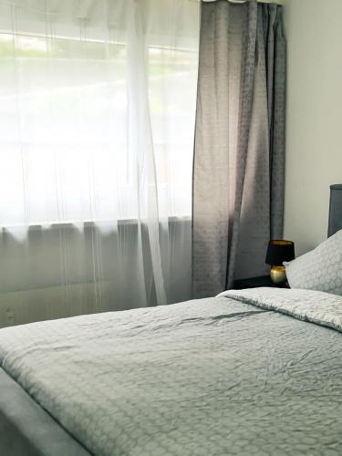 a bedroom with a white bed with a window at Nika Apartment - Aare Jungfrau AG in Grindelwald